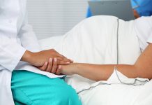 Friendly female medicine doctor hands holding pregnant woman's hand lying in bed for encouragement, empathy, cheering and support while medical examination. New life of abortion concept