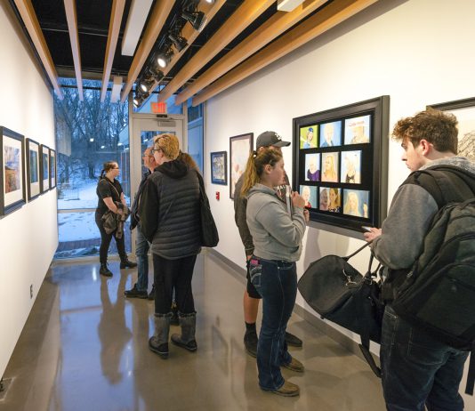 Visitors look at art on display in Kellogg Community College’s art gallery during the opening reception for the KCC Faculty Biennial Art Exhibition Jan. 24.