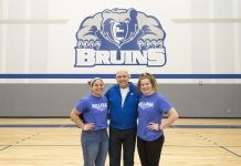 Volleyball players Madison Jones and Kameron Haley stand with Mick Haley in the Miller gym.