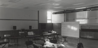 A black and white photo showing light falling through a window on a table in a classroom.