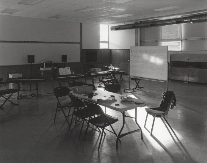 A black and white photo showing light falling through a window on a table in a classroom.
